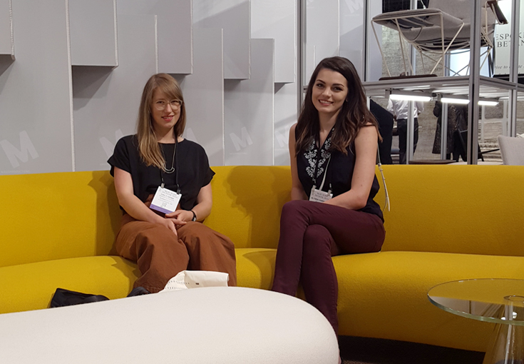 Two women sitting on a yellow couch at ICFF