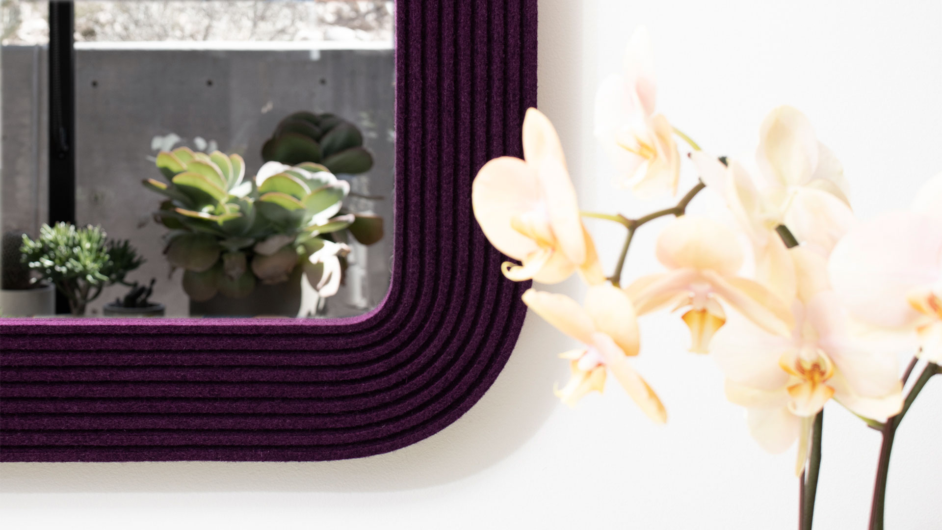 Closeup of the corner of eggplant felt frame of a mirror with plants