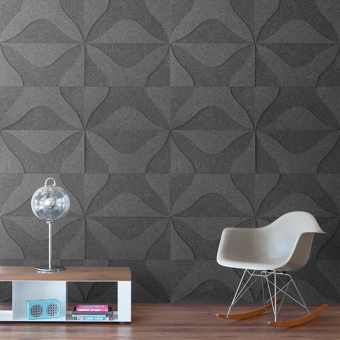 A room scene with a low table and Eames rocking chair. The wall is covered in a two tone gray felt wall covering. The pattern is a thick X