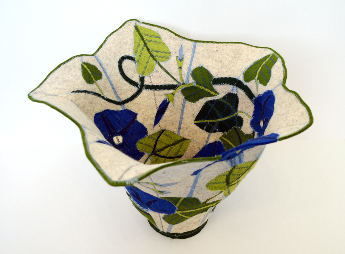 Large felt vessel with blue morning glories and leaves stitched on a light gray background