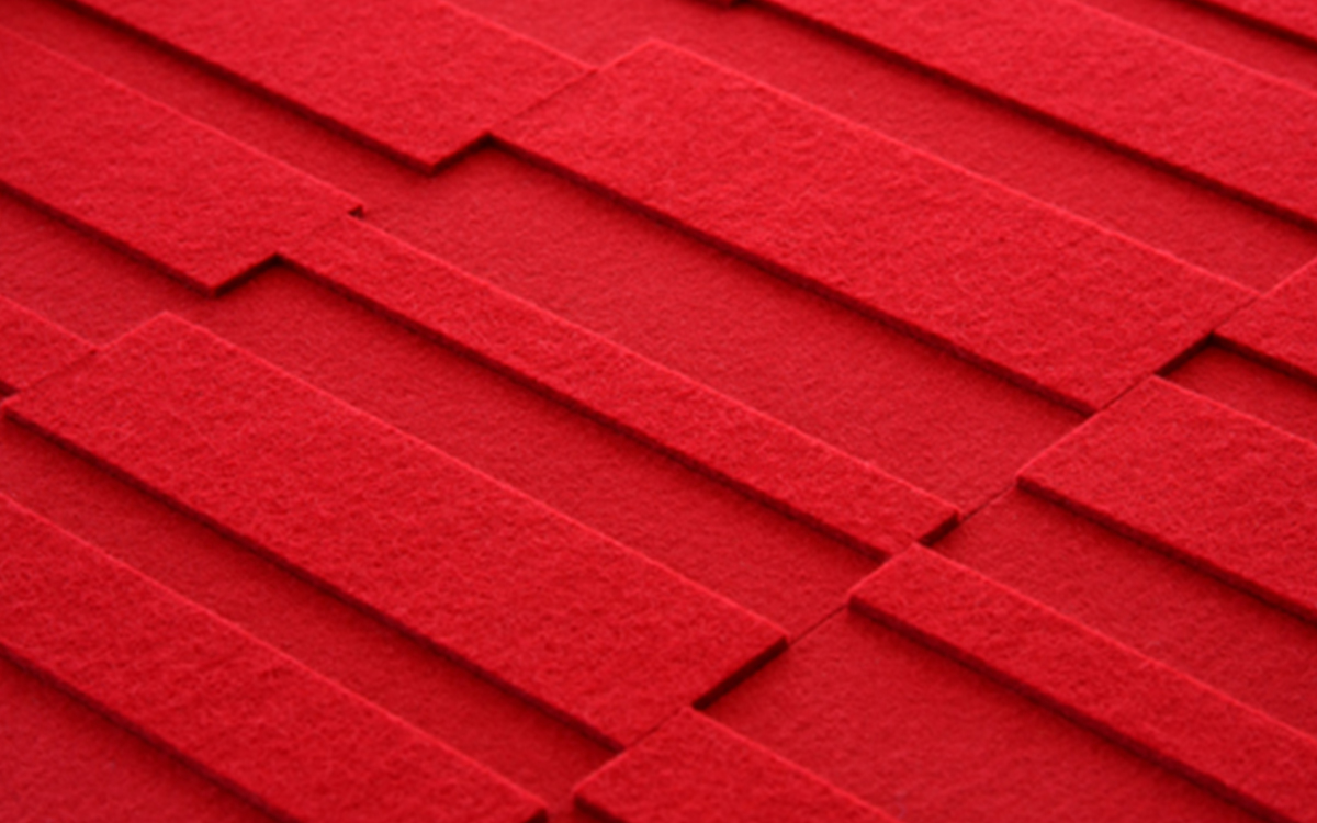 Closeup of red felt wallcovering with different height rectangular pieces.