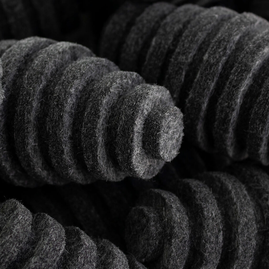 Closeup of pile of dark gray felt pods. They are oblong egg-shaped and have ridges.