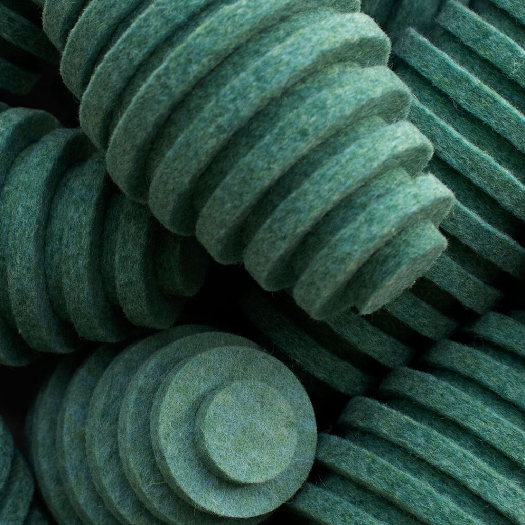 Closeup of pile of teal felt pods. They are oblong egg-shaped and have ridges.