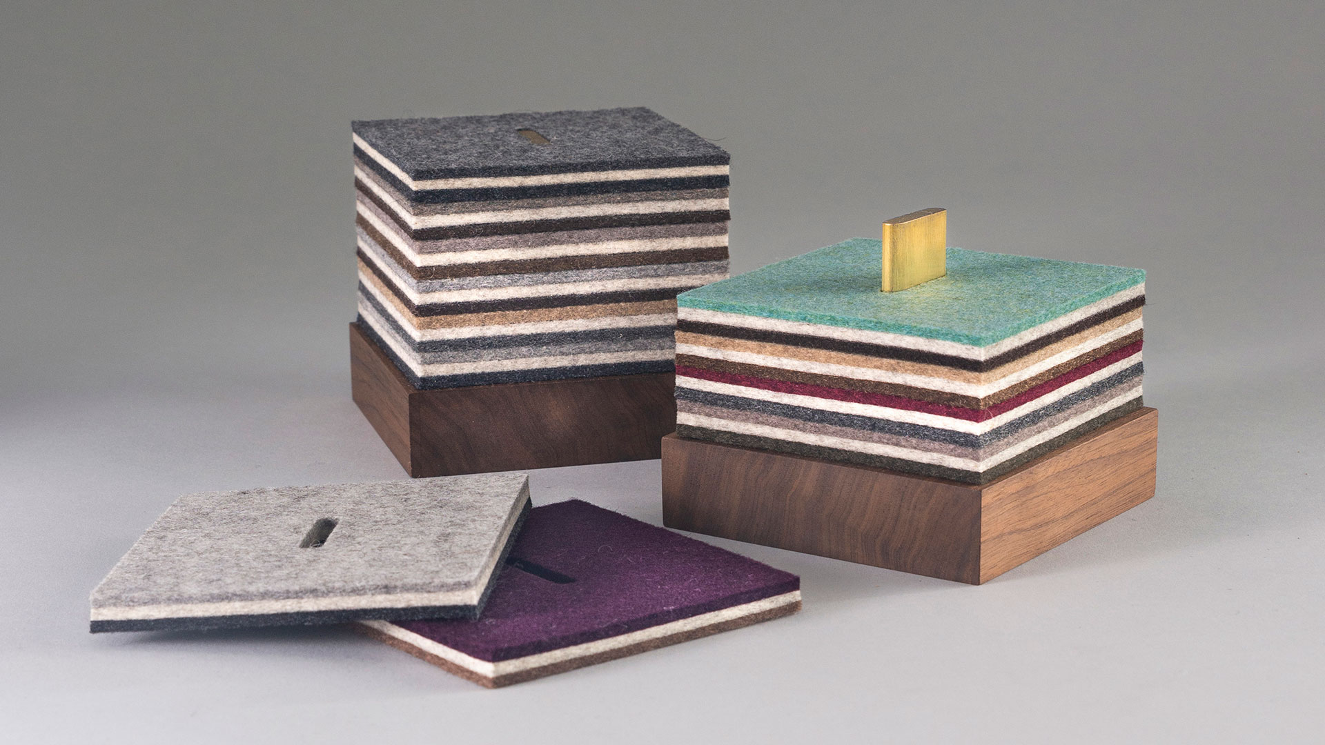 Two coaster sets with dark wood bases and layered multicolor felt square coasters