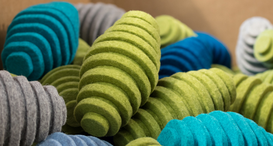Pile of blue, green and gray felt pods. They are oblong egg-shaped and have ridges.