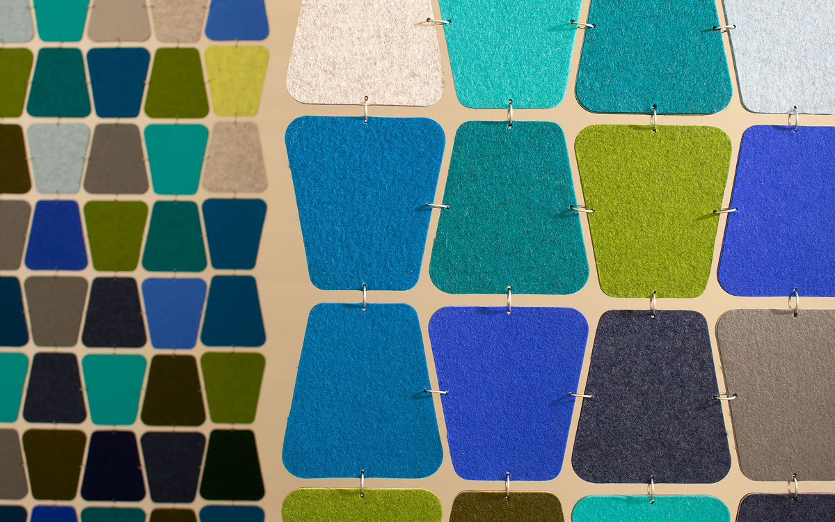 Closeup of softly curved trapezoid shaped felt pieces in blues and greens connected with metal rings.