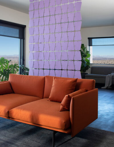 Lavender felt screen with rounded trapezoid shapes hangs behind a modern orange couch in a house