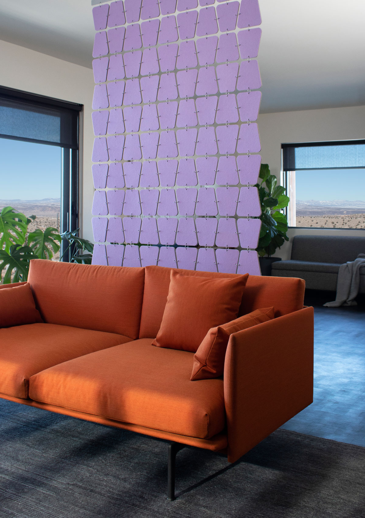 Lavender felt screen with rounded trapezoid shapes hangs behind a modern orange couch in a house