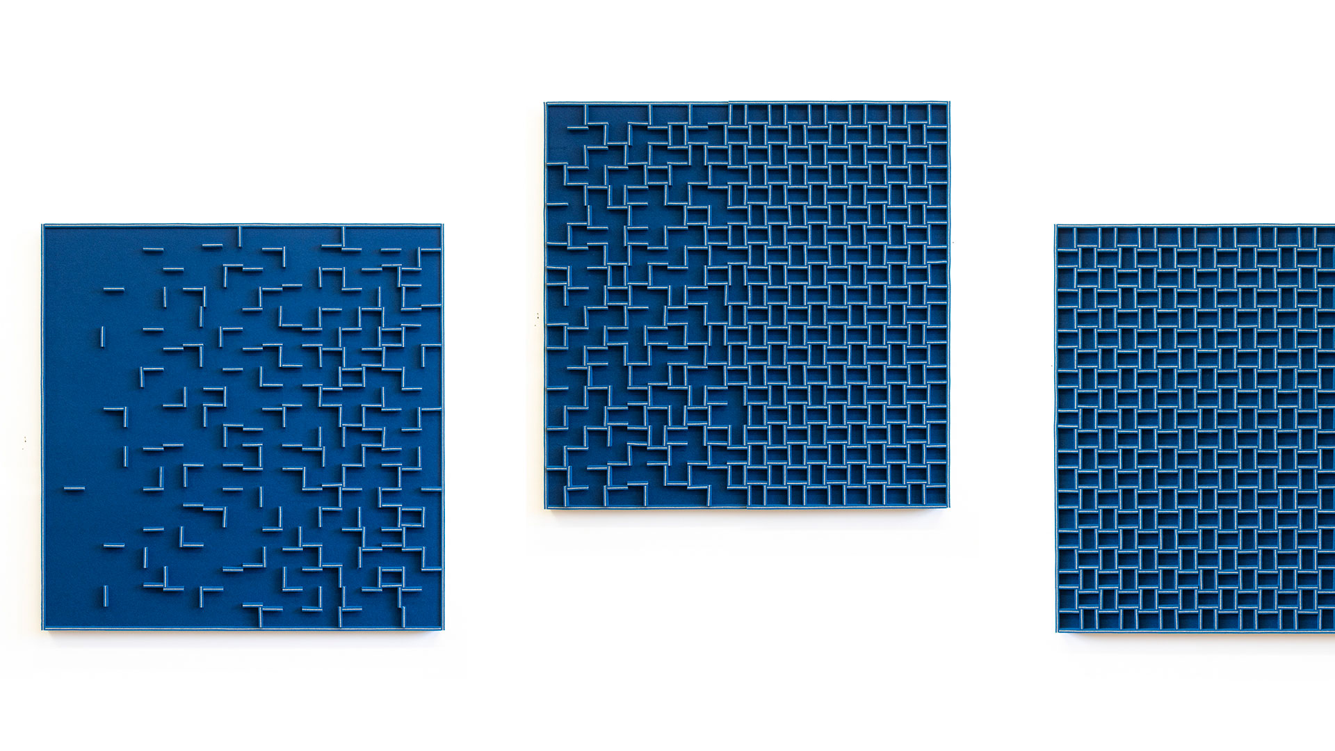 a trio of blue felt wall panels with a grid-like pattern that becomes looser on the panels at left