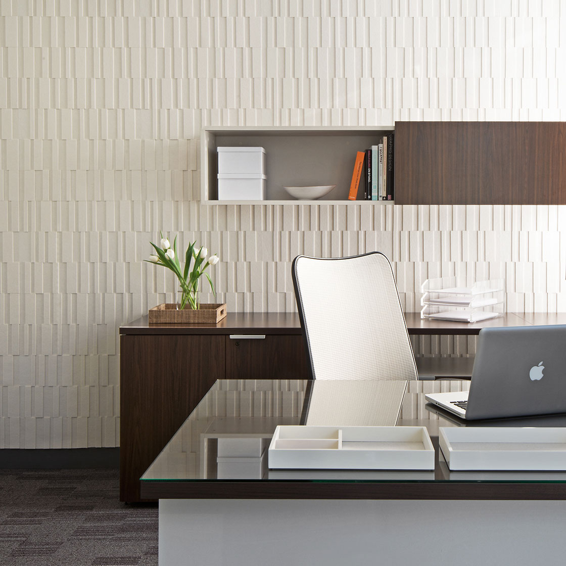 An office space with a cream felt wall covering with alternating vertical rectangular shapes.