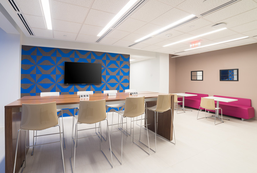 An office space wuth tables and chairs and a blue and gray wallcovering with thick X pattern