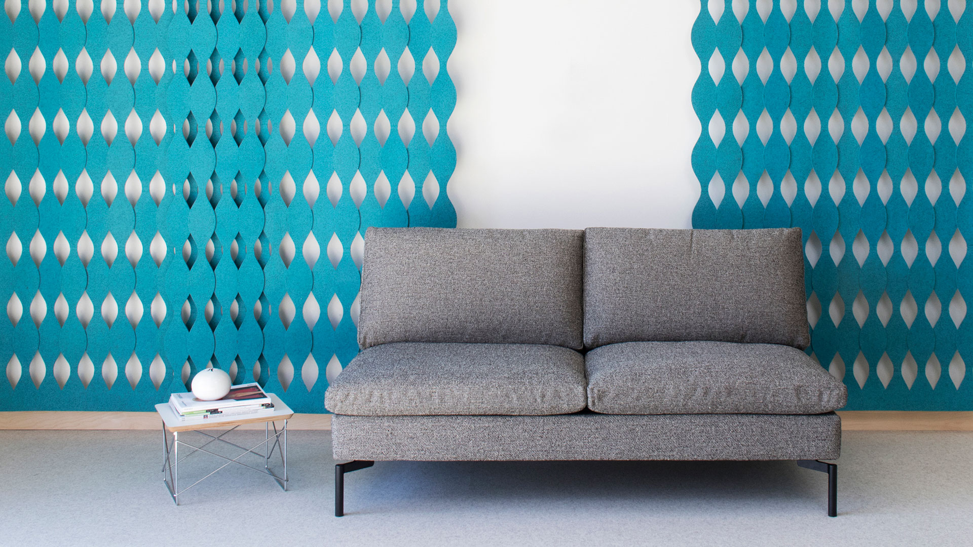 Gray couch and small table with blue felt wall screens in a curvy pattern