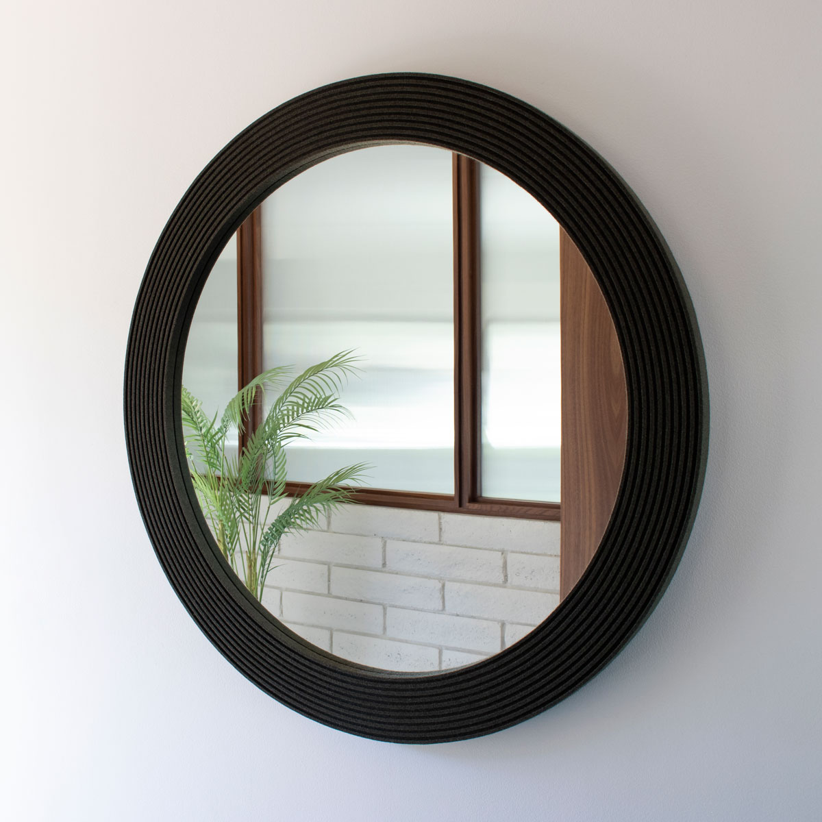circular mirror framed in dark olive ribbed felt