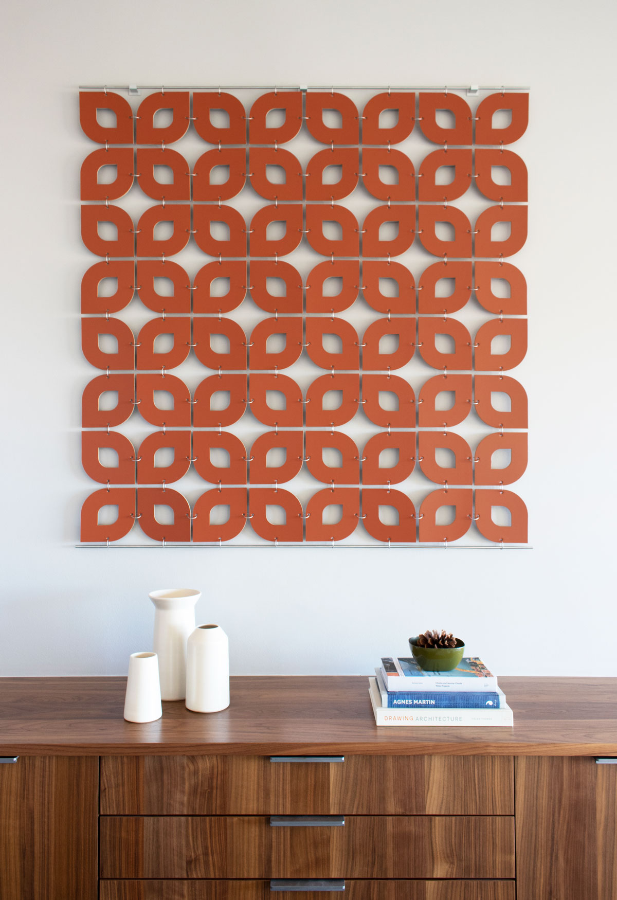 Deep orange leather wall hanging with curved forms connected by metal rings