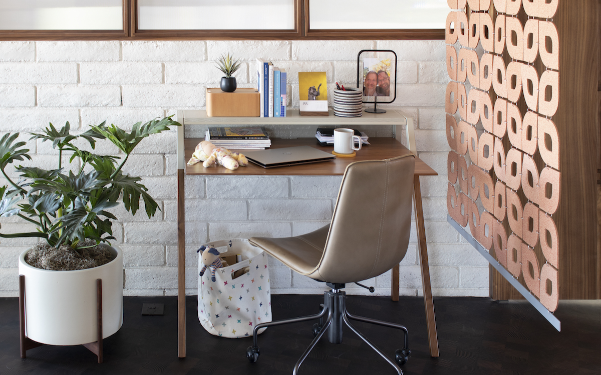 modern home office space with a potted plant and a small desk beside a cork space divider