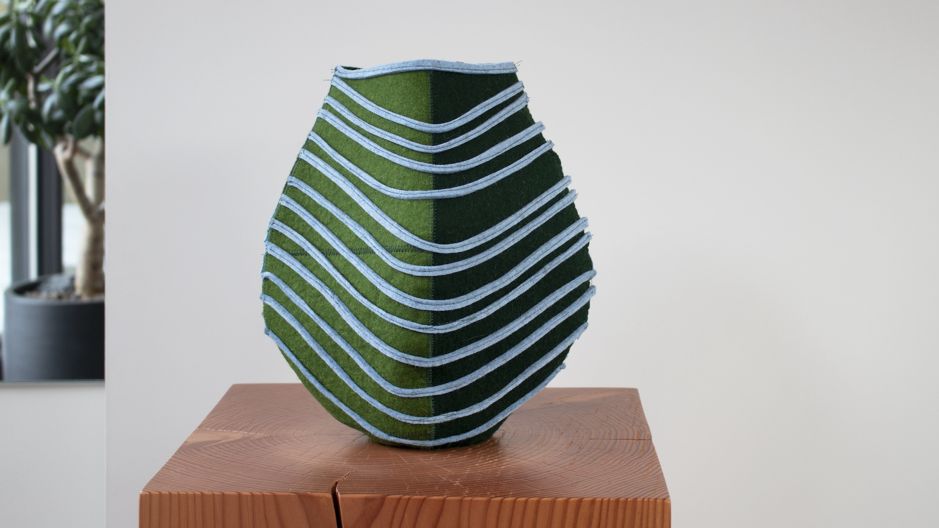 Blue and green striped vessel made of repurposed wool felt scraps from the manufacturing process