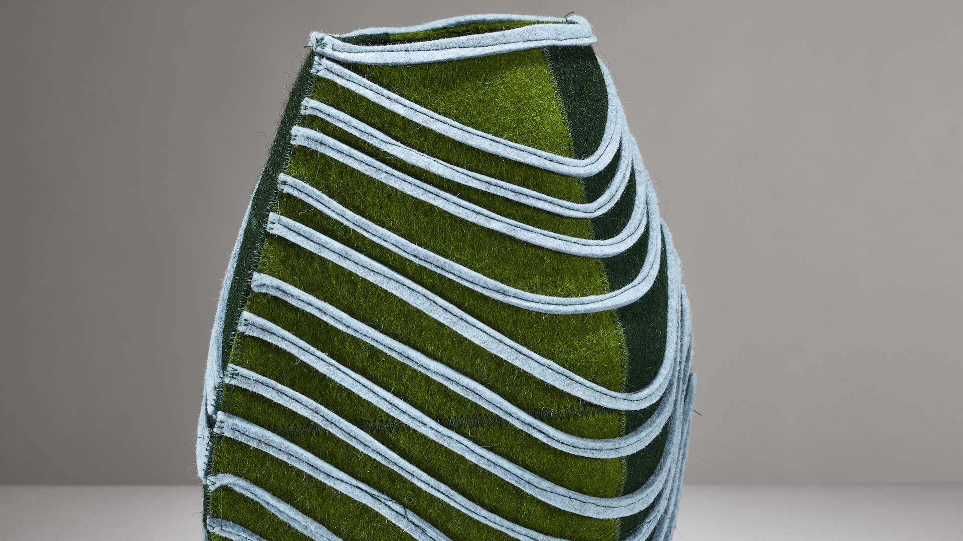 closeup of a vessel made from merino wool in shades of green and blue
