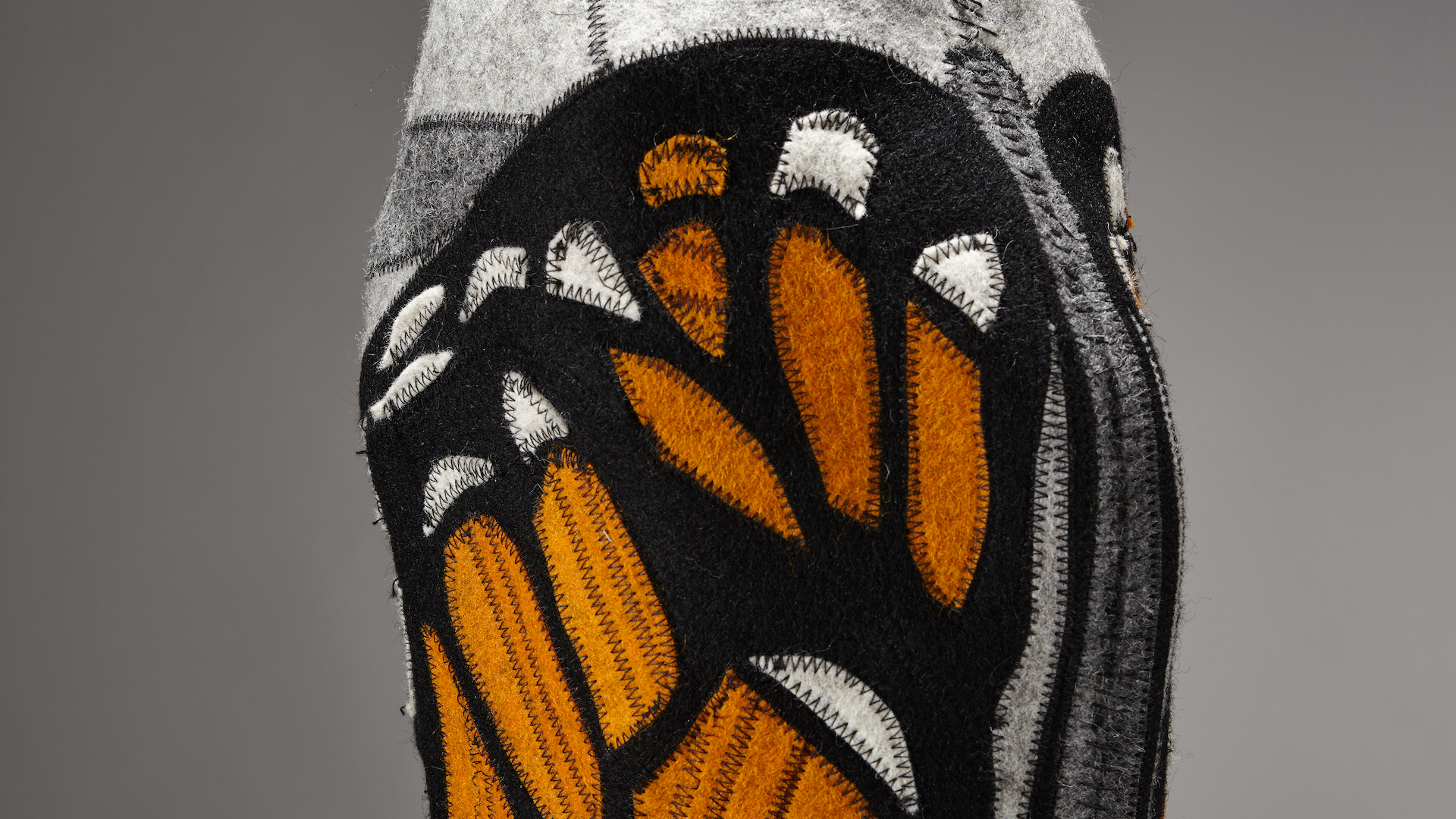 detail shot of monarch butterfly wing pattern on a vase sewn from wool offcuts