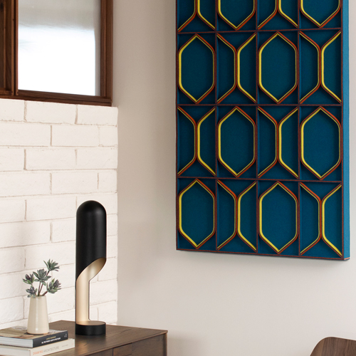 A modern wall panel in dark blue with red and yellow details hangs on an interior will behind a credenza