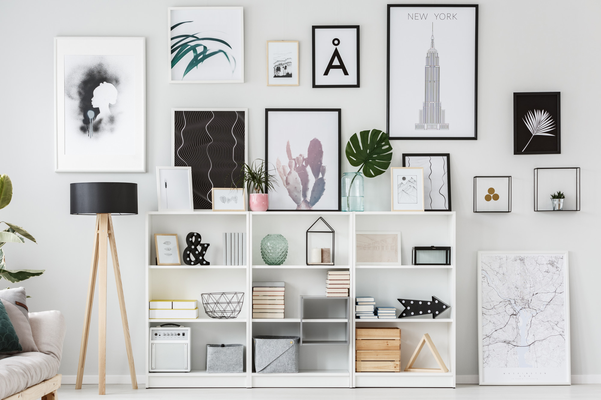 A bright white room with shelves full of books and accessories, and prints hanging on the wall
